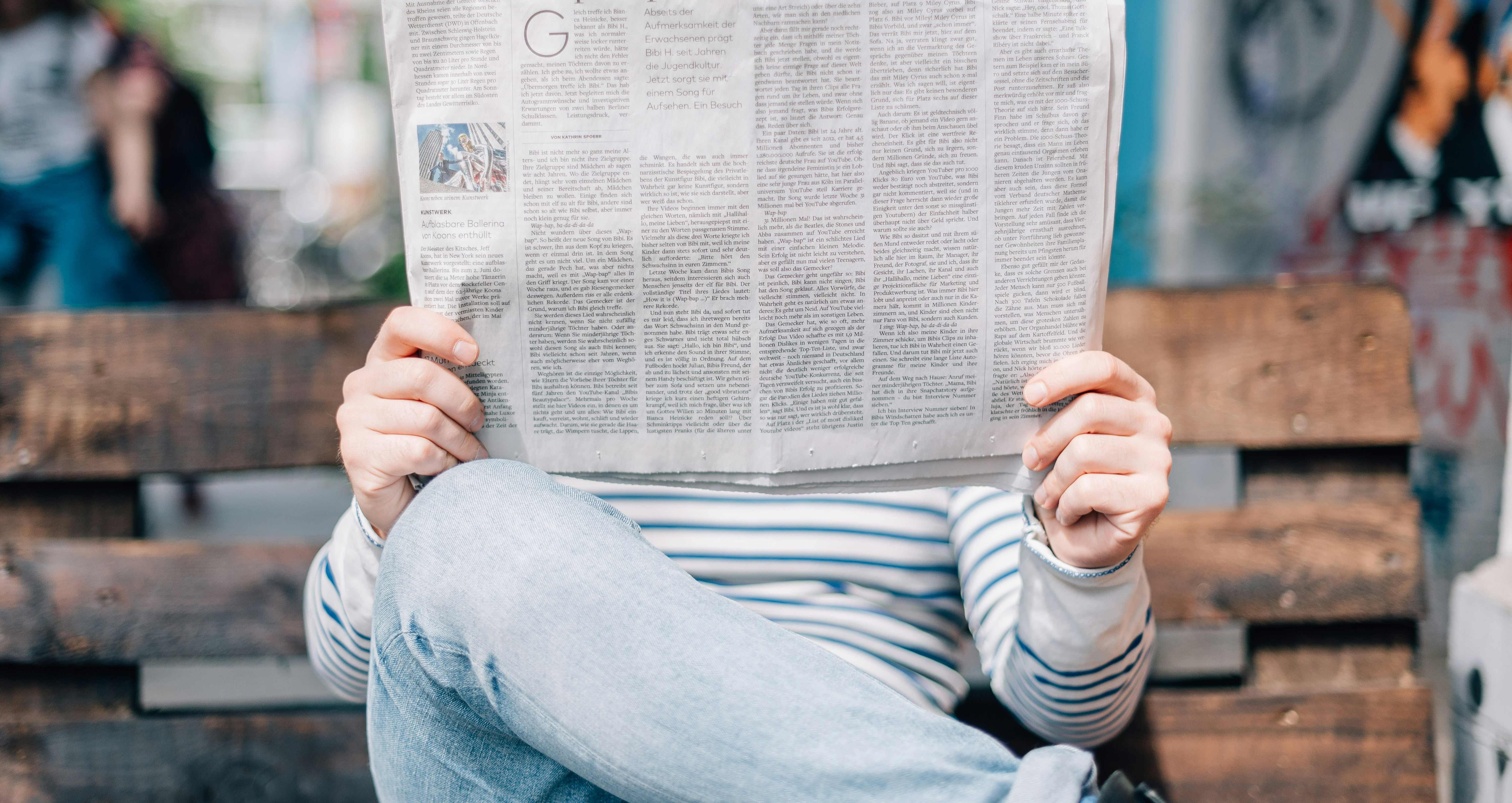 Person on bench reading newspaper