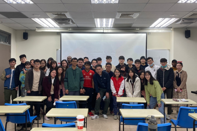 A large group of students posing in front of a projector.
