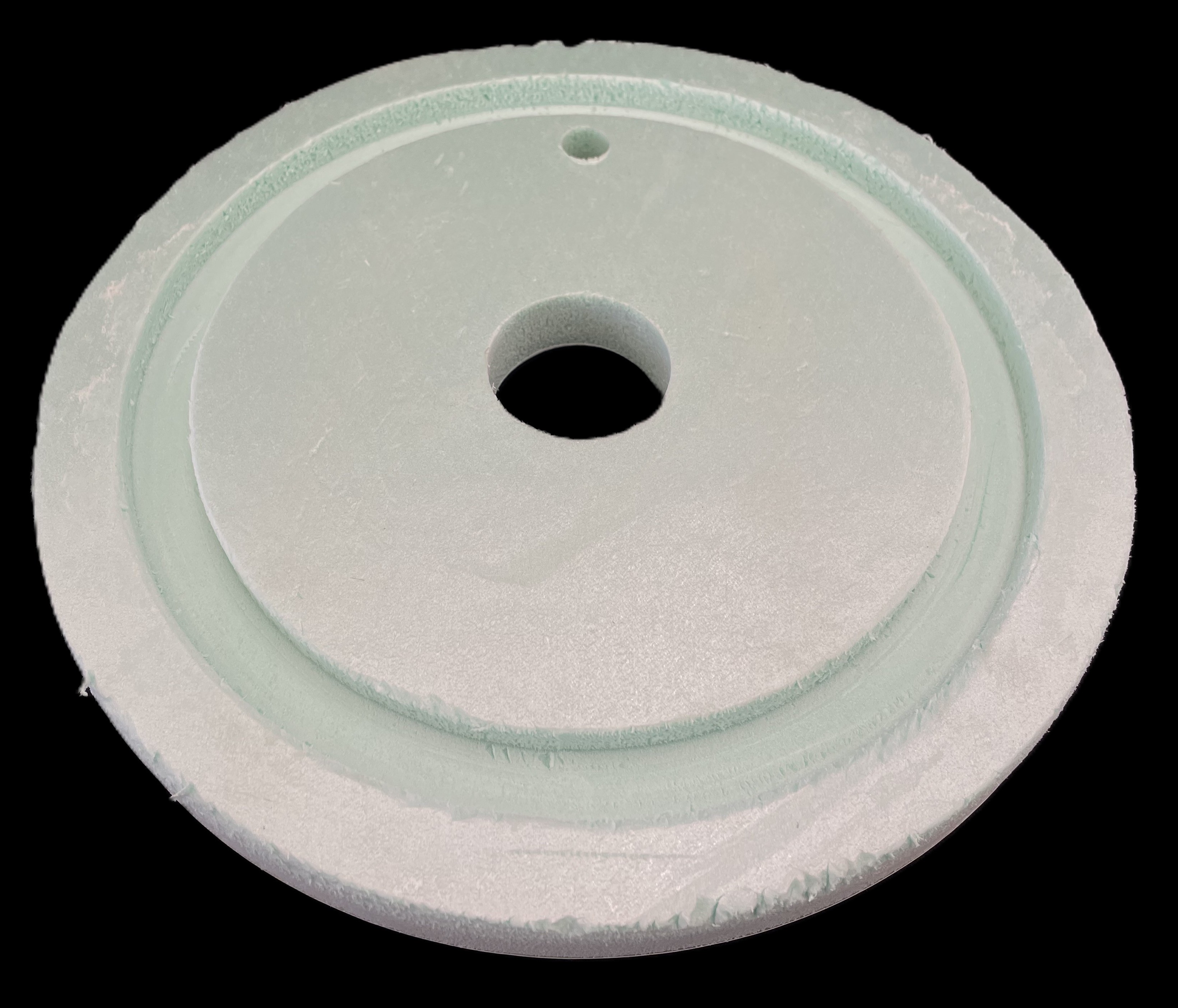 A green styrofoam circle with a pocket cut along the outside edge and two holes cut throughout the middle.