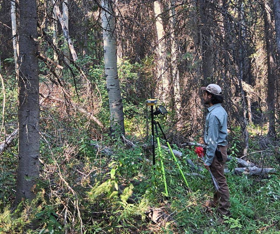 UFRI staff member in a forest using land survey equipment.
